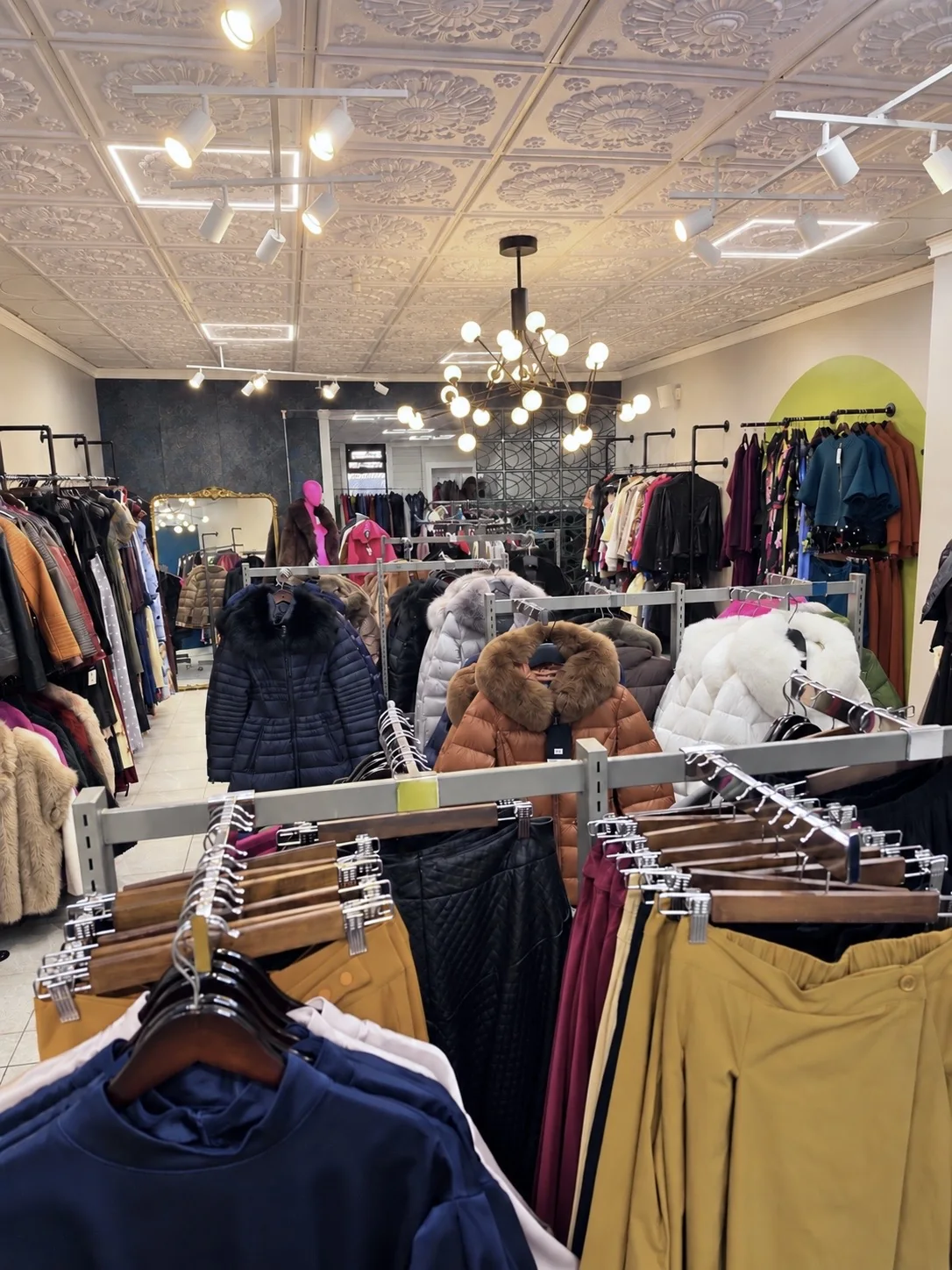 An overview of Bella's clothing collection beneath chandeliers and a patterned ceiling