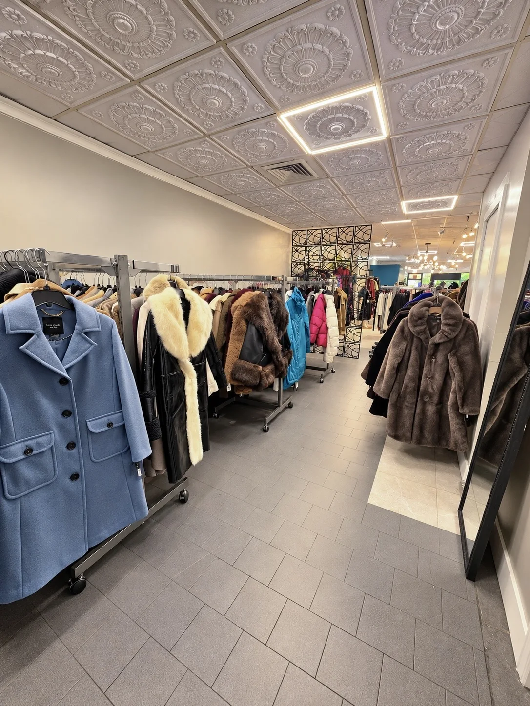 Racks of coats and outerwear, with a powder-blue coat in the foreground